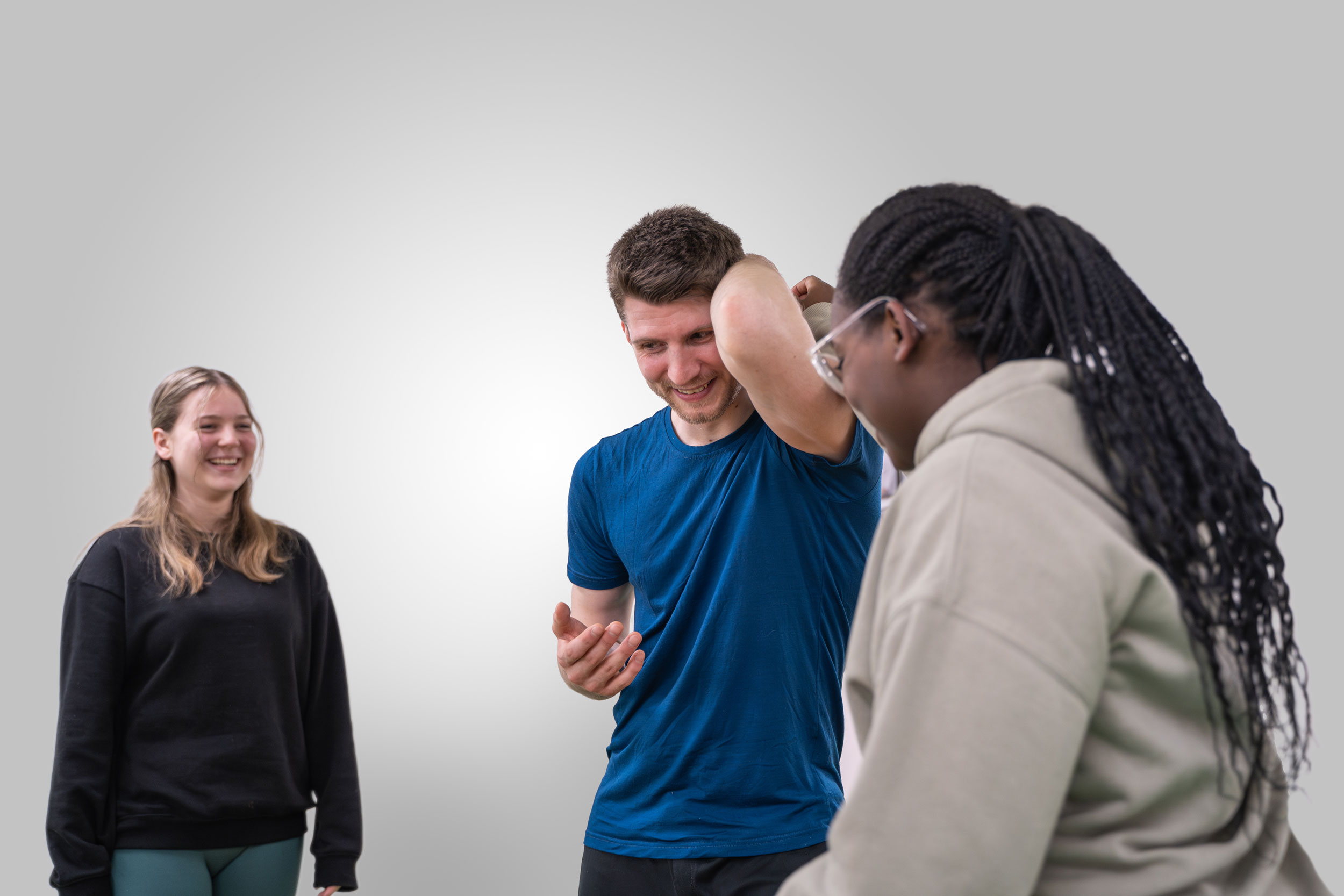 Trainer zeigt zwei jungen Frauen eine Übung